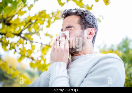 -MODELL VERÖFFENTLICHT. Junger Mann, Niesen, close-up. Stockfoto