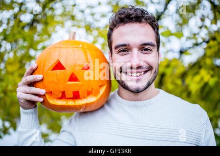 -MODELL VERÖFFENTLICHT. Porträt des jungen Mann, der Halloween-Kürbis hält. Stockfoto
