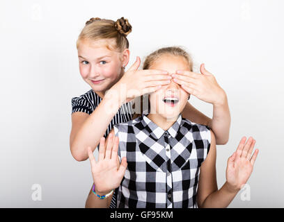 Zwei süße kleine Freundin mit dem Ausdruck ihrer verschiedene Emotionen. Lustige Kinder. Beste Freundinnen verwöhnen und posiert Stockfoto