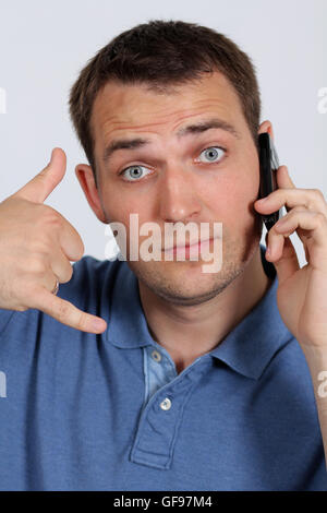Junger Mann mit einen Anruf mich Geste und ein Handy Stockfoto
