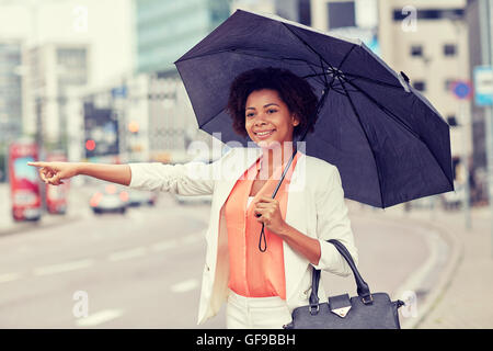 glücklich afrikanische Frau mit Regenschirm Fang taxi Stockfoto