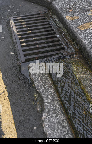 Straße Entwässerung/Rinne in Truro, Cornwall. Visuelle Metapher für "Geld in den Sand und Wasser/Abwasser. Stockfoto