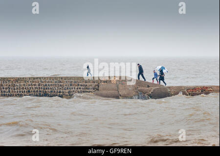 Familie Meer Sturm stürmischen Gefahr, eine Familie auf einem steinernen Steg Eile zurück zum Ufer, nachdem das Wetter plötzlich verschlechtert, Walton, UK Stockfoto