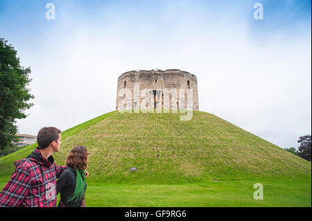 Clifford's Tower York UK, Blick auf Touristen, die am Norman Keep, auch bekannt als Clifford's Tower, im Zentrum der Stadt York, England, vorbeilaufen. Stockfoto