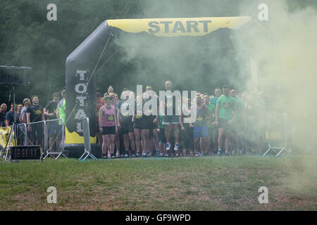 Gruppe von Wettbewerbern zu Beginn der Veranstaltung im Braham Park, Leeds, Total Warrior 2016 warten, als eine Rauchbombe die Luft füllt Stockfoto