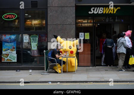 Pikachu entdeckt die kurze mollig gelb Pokemon unterwegs in Manchester auch unter eine Minute, um etwas zu Essen an der u-Bahn zu greifen. Stockfoto