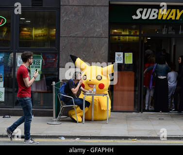 Pikachu entdeckt die kurze mollig gelb Pokemon unterwegs in Manchester auch unter eine Minute, um etwas zu Essen an der u-Bahn zu greifen. Stockfoto