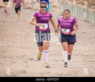 Las Palmas, Gran Canaria, Kanarische Inseln, Spanien. 30. Juli 2016. Mehr als 1.000 Frauen nehmen Teil an einem 12km Küsten Trail Rennen an der schroffen und vulkanische Nordküste in der Nähe von Las Palmas, der Hauptstadt von Gran Canaria. Bild: Zwei Frauen halten Hände als Thet Ansatz die Ziellinie. Bildnachweis: Alan Dawson News/Alamy Live-Nachrichten Stockfoto