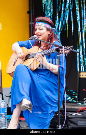 Kolumbianische Songwriter, Sänger und Gitarrist, Carolina Herrera in blauem Kleid, Gitarre spielen und Singen, während auf einer Open Air Bühne in Ramsgate. Stockfoto