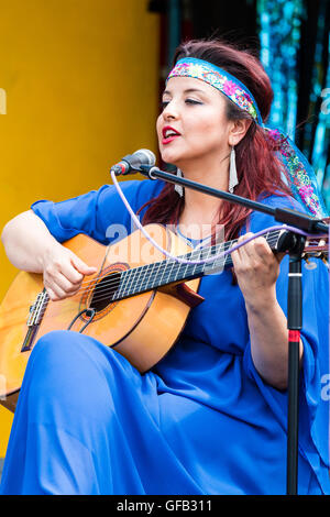 Kolumbianische Songwriter, Sänger und Gitarrist, Carolina Herrera in blauem Kleid, Gitarre spielen und Singen, während auf einer Open Air Bühne in Ramsgate. Stockfoto