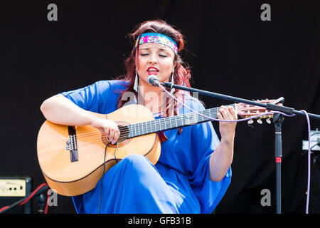 Kolumbianische Songwriter, Sänger und Gitarrist, Carolina Herrera in blauem Kleid, Gitarre spielen und Singen, während auf einer Open Air Bühne in Ramsgate. Stockfoto