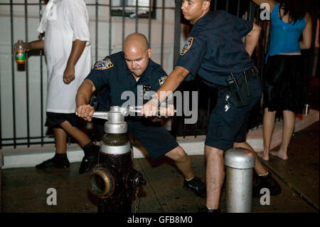 NYPD-Polizisten Herunterfahren ein illegal eröffneten Hydranten in Harlem in New York City, USA, 2. August 2006 Stockfoto