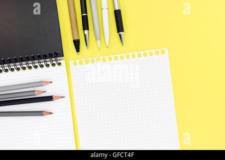 leer Merkzettel, Blatt weißes Papier, Kugelschreiber und Graphitstifte auf gelbem Hintergrund Stockfoto