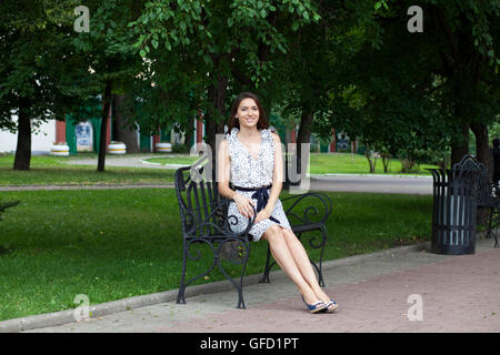 Schöne junge Frau sitzt auf einer Bank Stockfoto