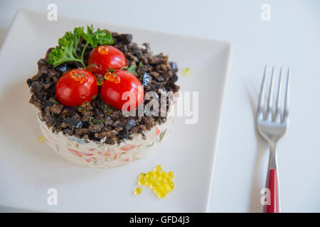 Russischer Salat mit Cherry-Tomaten, schwarzen Oliven, Petersilie und Perlen von Olivenöl. Stockfoto