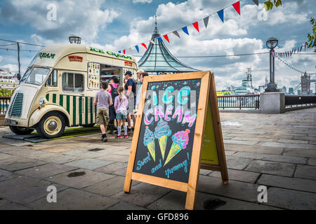 Familien in der Schlange vor einem Eiswagen neben dem London Bridge City Pier an der Themse in London, Großbritannien Stockfoto