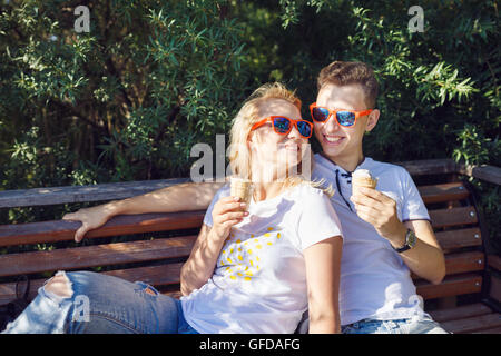 Junges Paar essen Eis beim Sitzen auf der Bank, Sommerzeit Stockfoto