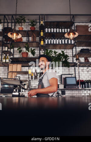 Porträt der jungen Unternehmer stehen in einem Café. Hübscher junger Mann trägt Schürze tatenlos bar Theke wegschauen und Stockfoto