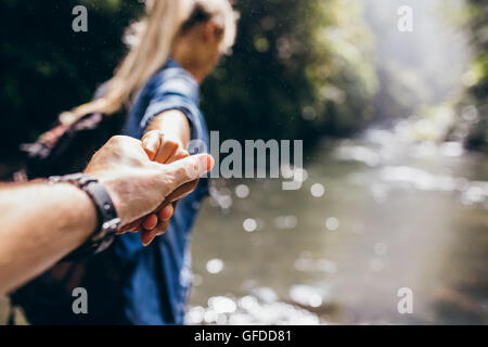 Zwei Wanderer in der Natur. Nahaufnahme von Mann und Frau, die Hand in Hand bei der Überquerung des Baches. Hände des Paares im Mittelpunkt. Stockfoto