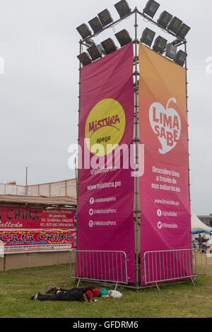 Lima, Peru - 11. September 2015: Menschen schlafen vor einem Mistura Festival-Wegweiser Stockfoto