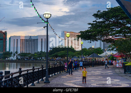 Kuching Stadt am Wasser bei Sonnenuntergang. Die Menschen gehen auf der Straße. Sarawak. Borneo. Stockfoto