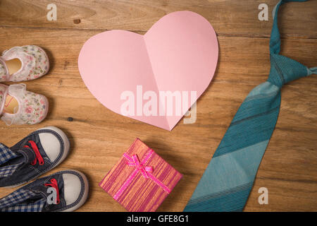 Daddy es Stiefel, Baby Schuhe, Textile Herzen, Geschenk und blaue Krawatte auf hölzernen Hintergrund .fathers Tag Konzept, Vintage Farbe Stockfoto