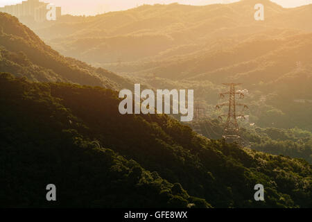 Freileitungsmasten Hochspannung mit Bergen im Hintergrund, Sonnenuntergang Stockfoto