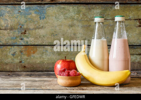 Zwei kleine Flaschen frischen Smoothie mit Zutaten um auf Holz Hintergrund mit Textfreiraum. Banane, Apfel und Himbeeren wi Stockfoto