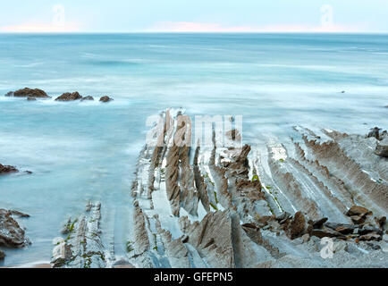 Dämmerung Ozeanküste mit gerippten stratiforme Felsformationen. (Atlantik, Spanien). Stockfoto