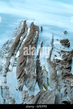 Dämmerung Ozeanküste mit gerippten stratiforme Felsformationen. (Atlantik, Spanien). Stockfoto