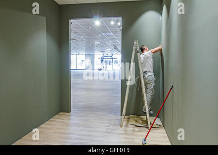 Arbeitnehmer werden verwendet, Holzleiter, moderne Office-Decke mit Luftkanal und Lampen abzuschließen. Stockfoto