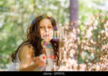 schöne Reife Dame zu jagen und zu versuchen zu fangen Seifenblase mit Zauberstab Stockfoto