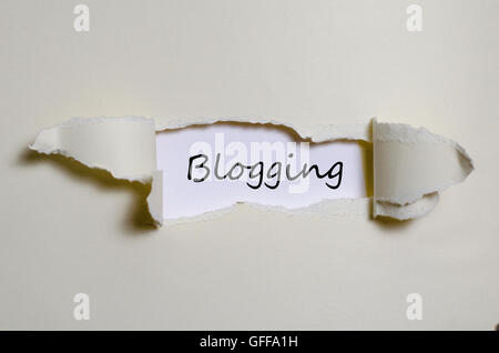 Das Wort Blogging erscheint hinter zerrissenes Papier Stockfoto