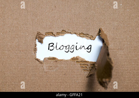 Das Wort Blogging erscheint hinter zerrissenes Papier Stockfoto