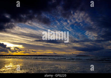 Sonnenuntergang am Penmaenmawr Beach in Richtung Anglesey Stockfoto