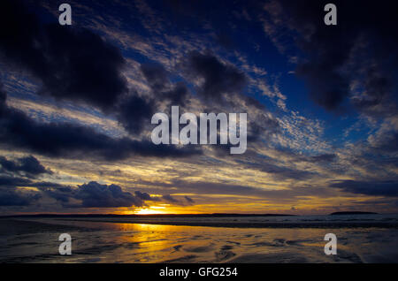 Sonnenuntergang am Penmaenmawr Beach in Richtung Anglesey Stockfoto