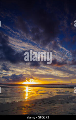 Sonnenuntergang am Penmaenmawr Beach in Richtung Anglesey Stockfoto