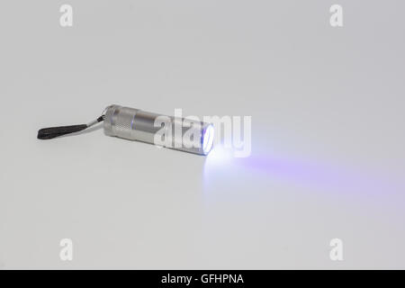 kleine Taschenlampe arbeiten auf einem weißen Hintergrund mit einem Strahl von Licht Stockfoto