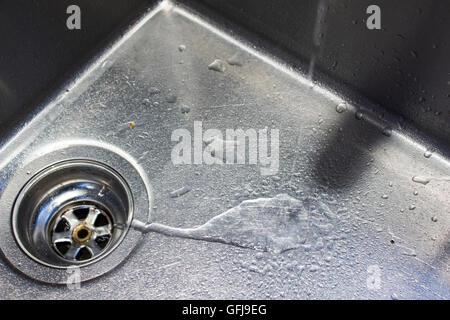 Wasser aus einem Hahn läuft den Bach runter in eine Edelstahl-Spüle Stockfoto