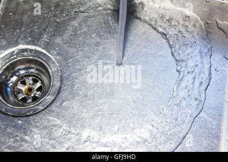 Wasser aus einem Hahn läuft den Bach runter in eine Edelstahl-Spüle Stockfoto