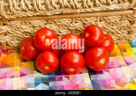 Tomaten gegen ein geflochtener Korb gestapelt Stockfoto