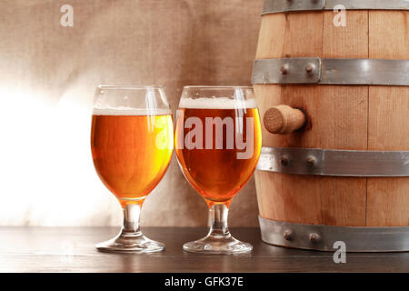 Zwei Gläser Bier in der Nähe von Holzfass auf Leinwand Hintergrund Stockfoto