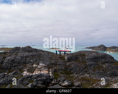 Touristen auf Hügel oberhalb Paamiut Stadt Grönland Blick hinunter auf festgemachten Kreuzfahrtschiffe und Royal Arctic Line Containerschiff auf Kuannersooq-Fjord Stockfoto