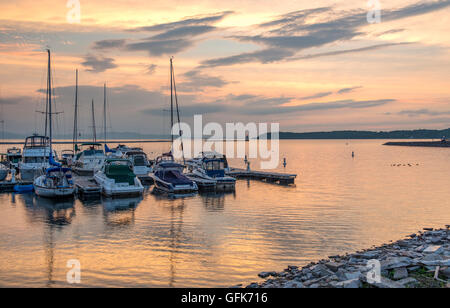 Farbenfrohe Sonnenuntergangsszene mit Booten am Lake Champlain, Burlington Vermont mit Blick auf den Leuchtturm und die Berge im Hintergrund. Stockfoto