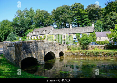 Hübschen Cotswold Steinbrücke über den Fluss Coln mit The Swan Hotel nach hinten, Bibury, Cotswolds, Gloucestershire, England, Stockfoto