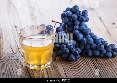 Frische schwarze Trauben und frisch gepressten Trauben Saft auf rustikalen Holztisch, Ernte Zeit, selektiven Fokus Stockfoto