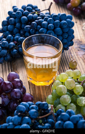 Frischen Weintrauben und frisch gepressten Traubensaft Saft auf rustikalen Holztisch, Erntezeit Stockfoto