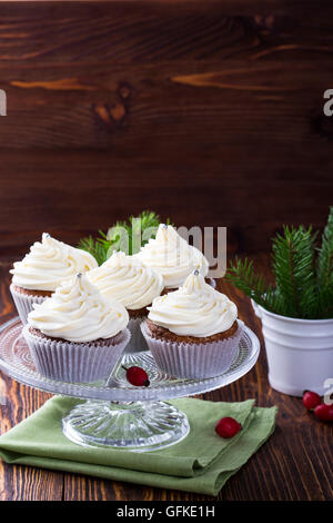 Hausgemachte Weihnachts Cupcakes mit Frischkäse frosting auf hölzernen Hintergrund mit Fichte Zweige in Keramik Eimer und Apfel-Cidre Stockfoto