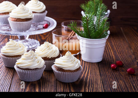 Hausgemachte Weihnachts Cupcakes mit Frischkäse frosting auf hölzernen Hintergrund mit Fichte Zweige in Keramik Eimer und Apfel-Cidre Stockfoto