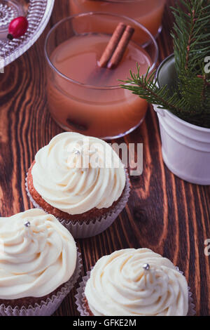 Hausgemachte Weihnachts Cupcakes mit Frischkäse frosting auf hölzernen Hintergrund mit Fichte Zweige in Keramik Eimer und Apfel-Cidre Stockfoto